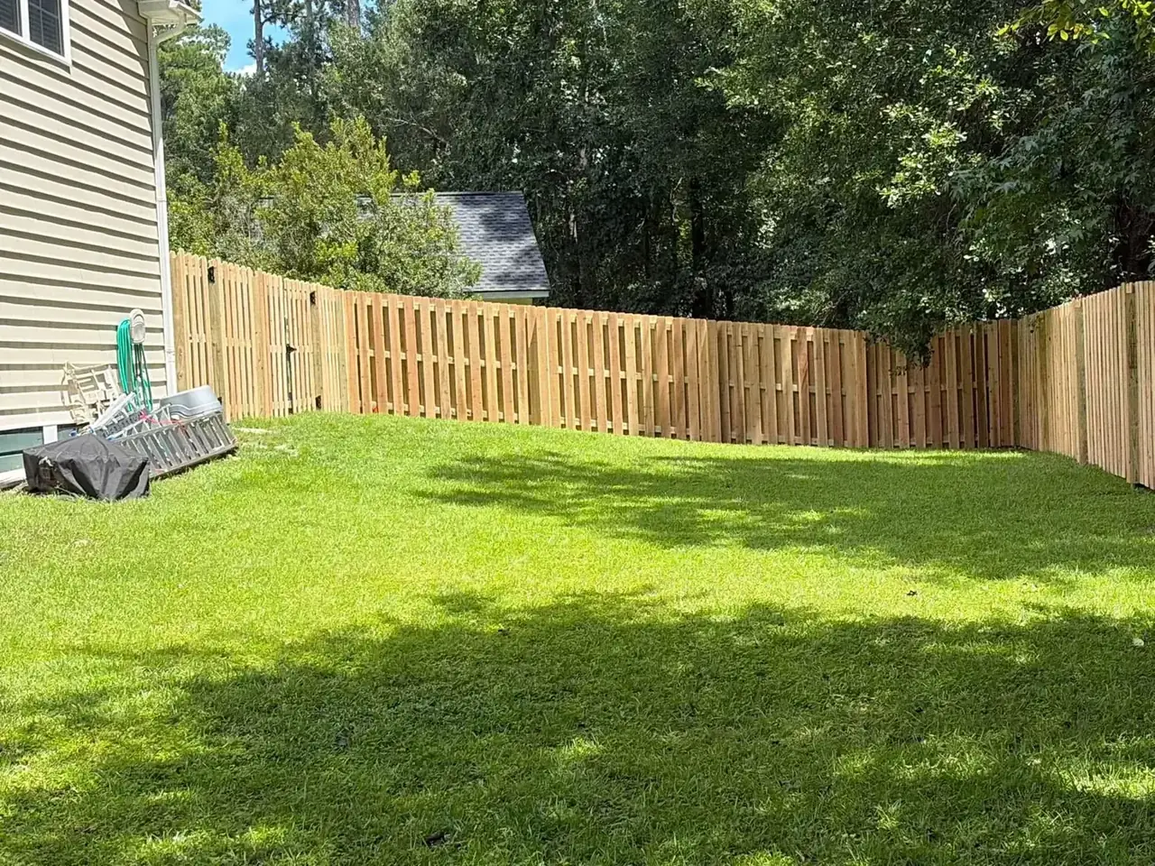 Wood privacy fence enclosing a green backyard
