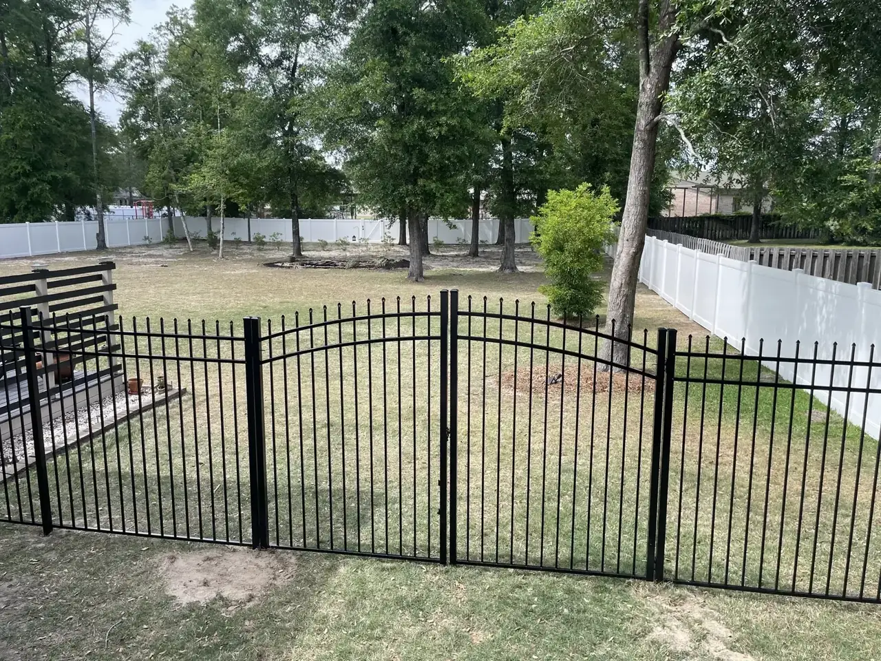 Black aluminum double gate beside white vinyl fencing